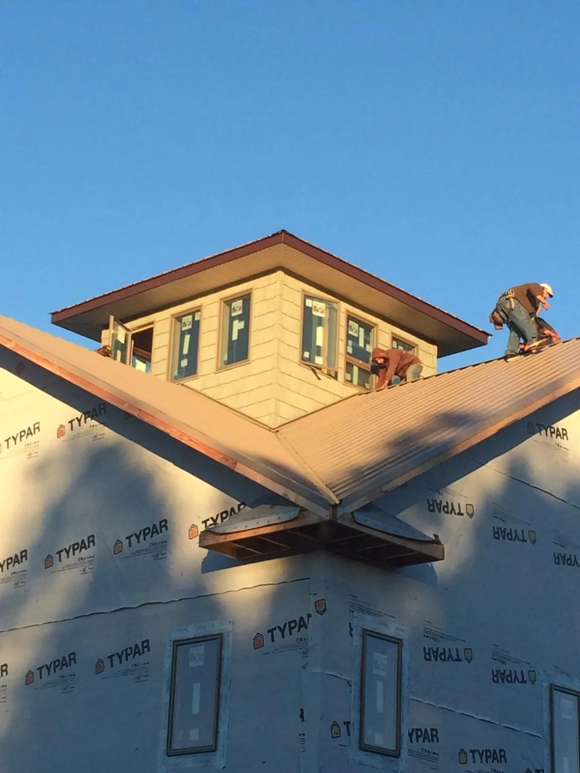 Roofers working around a rooftop cupola on a new metal roof at sunset — Roof Waterproofing in Hebron by Roofing Brothers